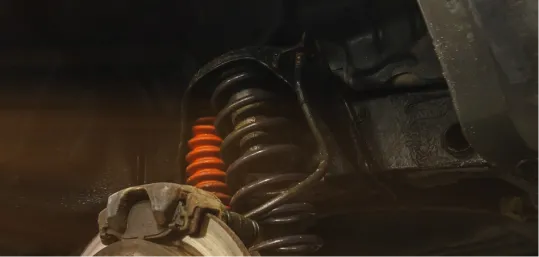Car suspension system with a red coil spring and brake components.