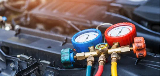 Manifold gauge set connected to a car engine for AC diagnostics.
