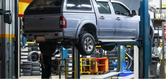 SUV elevated on a hydraulic lift in a tire and auto repair shop.