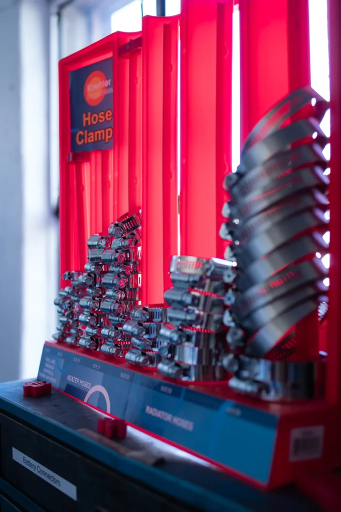 A close-up display of numerous silver metal hose clamps organized on a red stand.