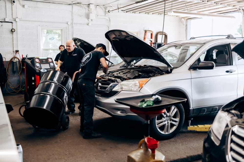 Trusted Auto Repair in Westfield, MA at LaFlamme's Auto & Truck Services. Three mechanics working in an auto repair shop, with one inspecting a vehicle engine while the doing other services